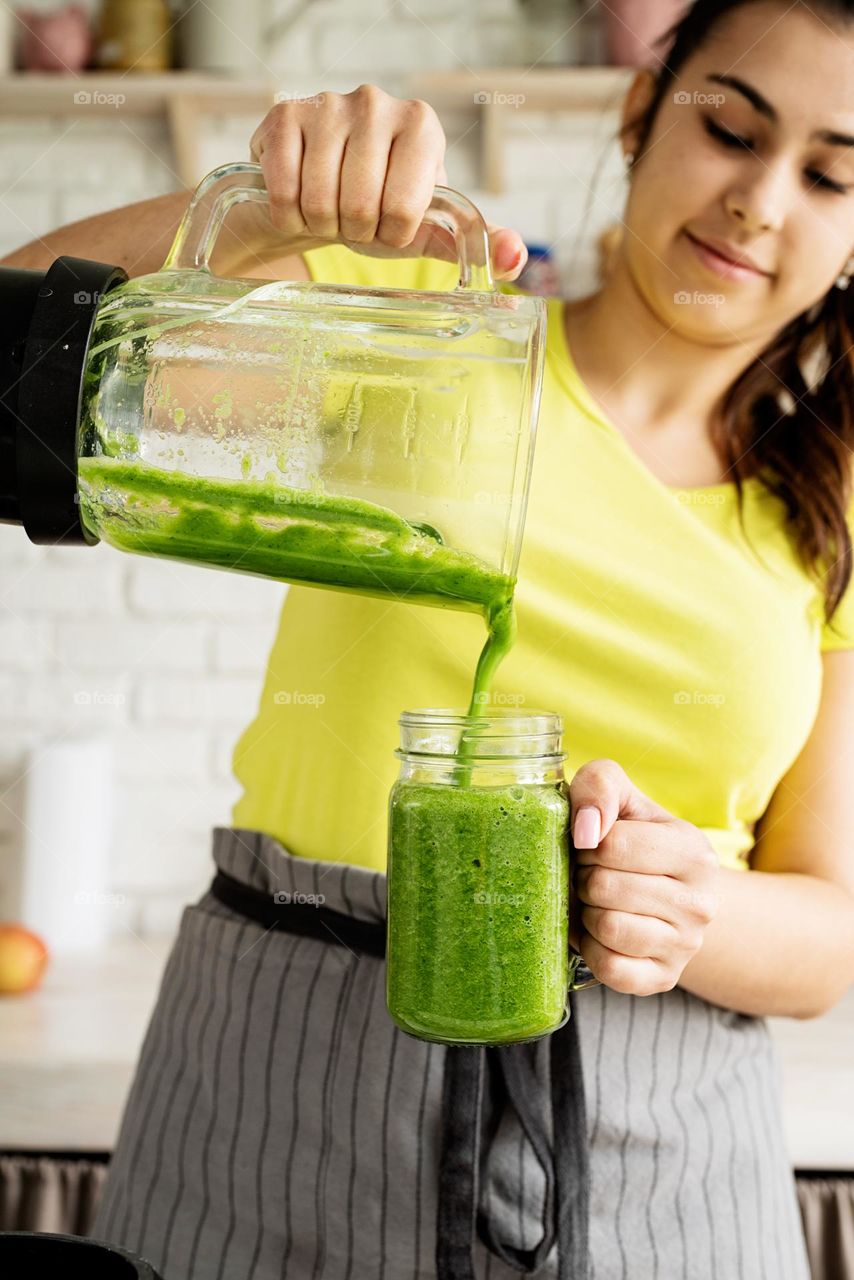 woman pouring out green smoothie