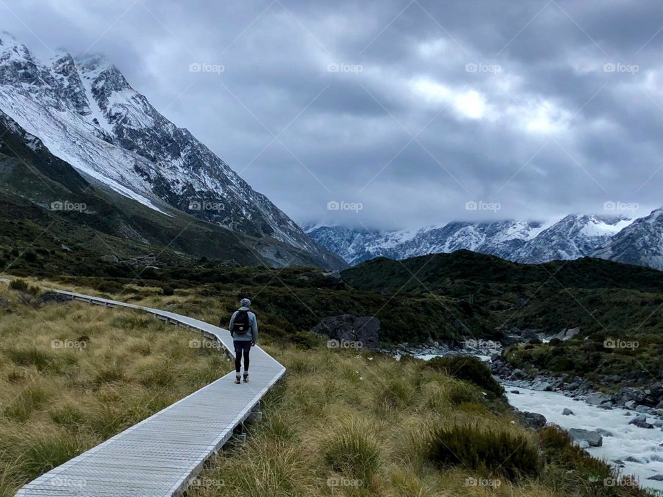 Taking a stroll along a boardwalk in Mt Cook National Park with snow dusted atop the mountains