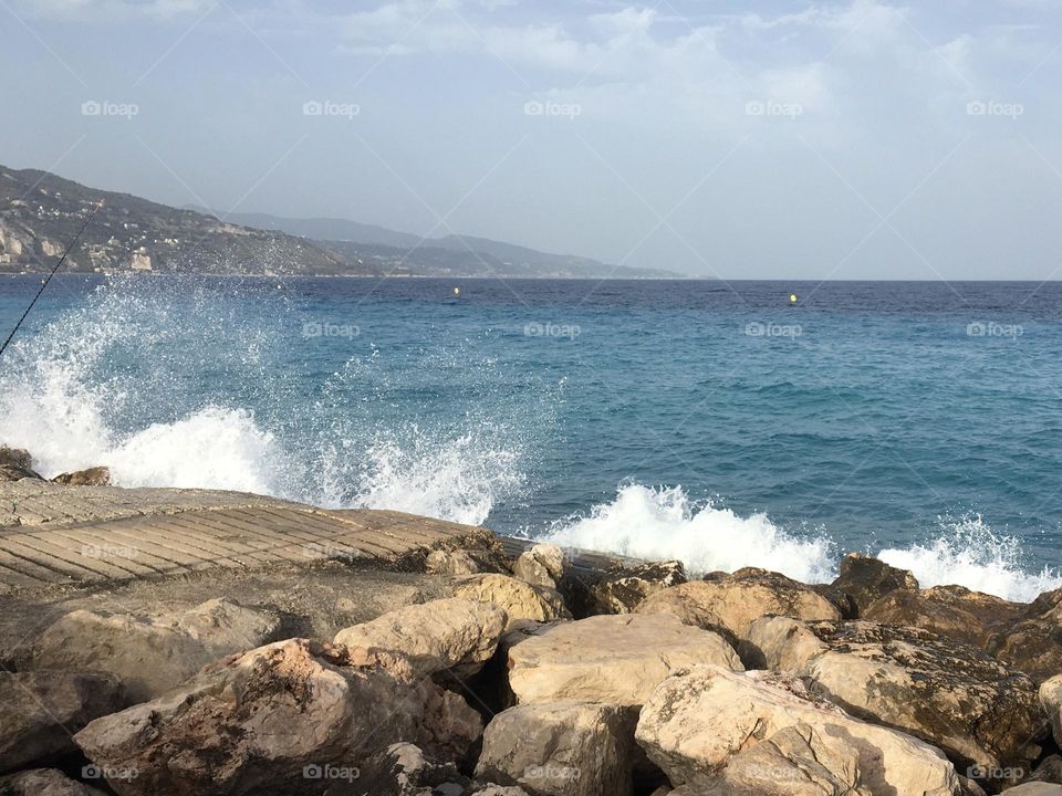 Waves on rocks with view on Italian coastline 