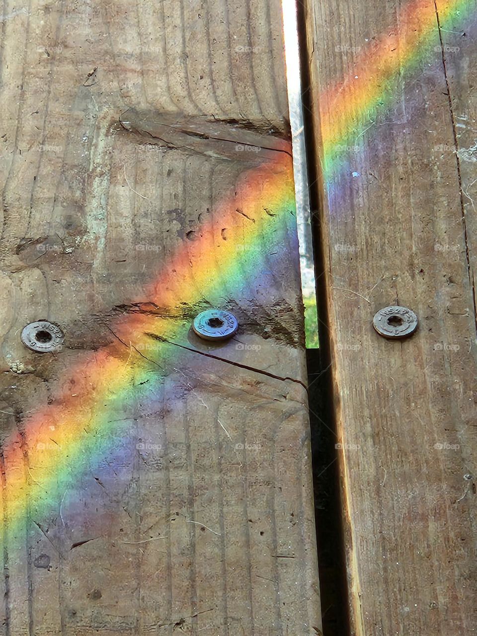 Rainbow line reflection from glass on wood planks