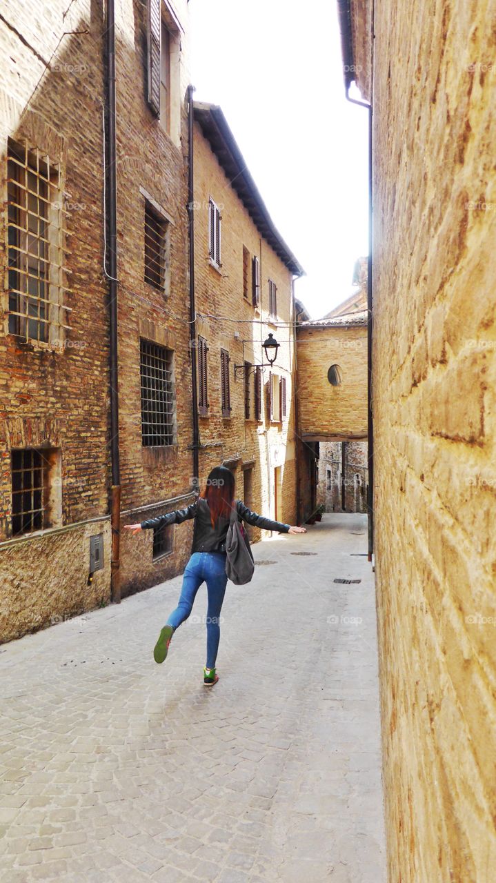 In the middle of a town. A Woman is standing on one leg in a road of a small town 