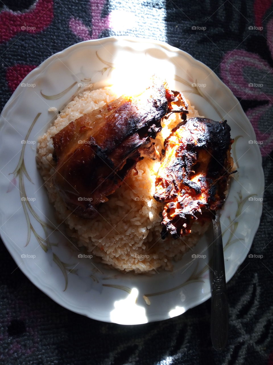 A dish of rice and two pieces of grilled chicken