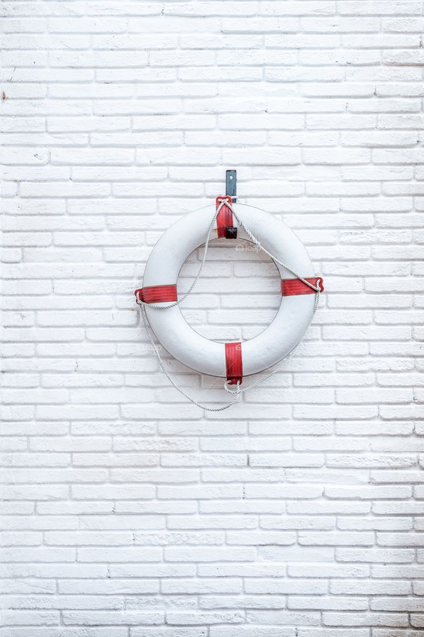 White lifebuoy on a white brick wall