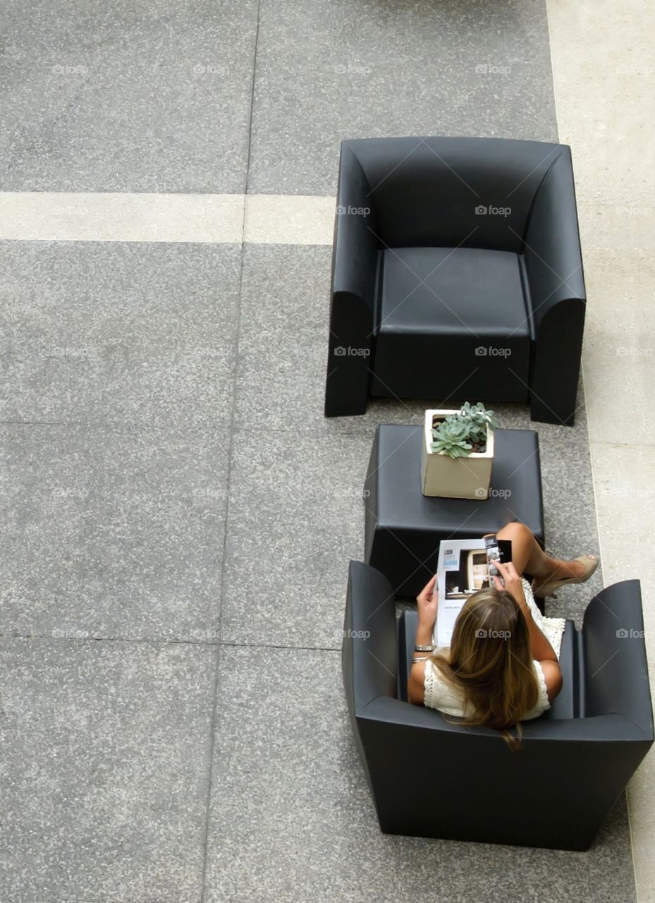 Girl in chair reading magazine from above