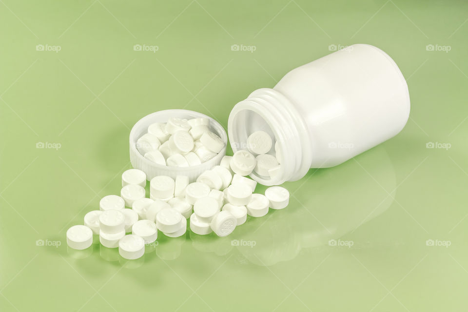 White pills and pill bottle. White pills and pill bottle on green background