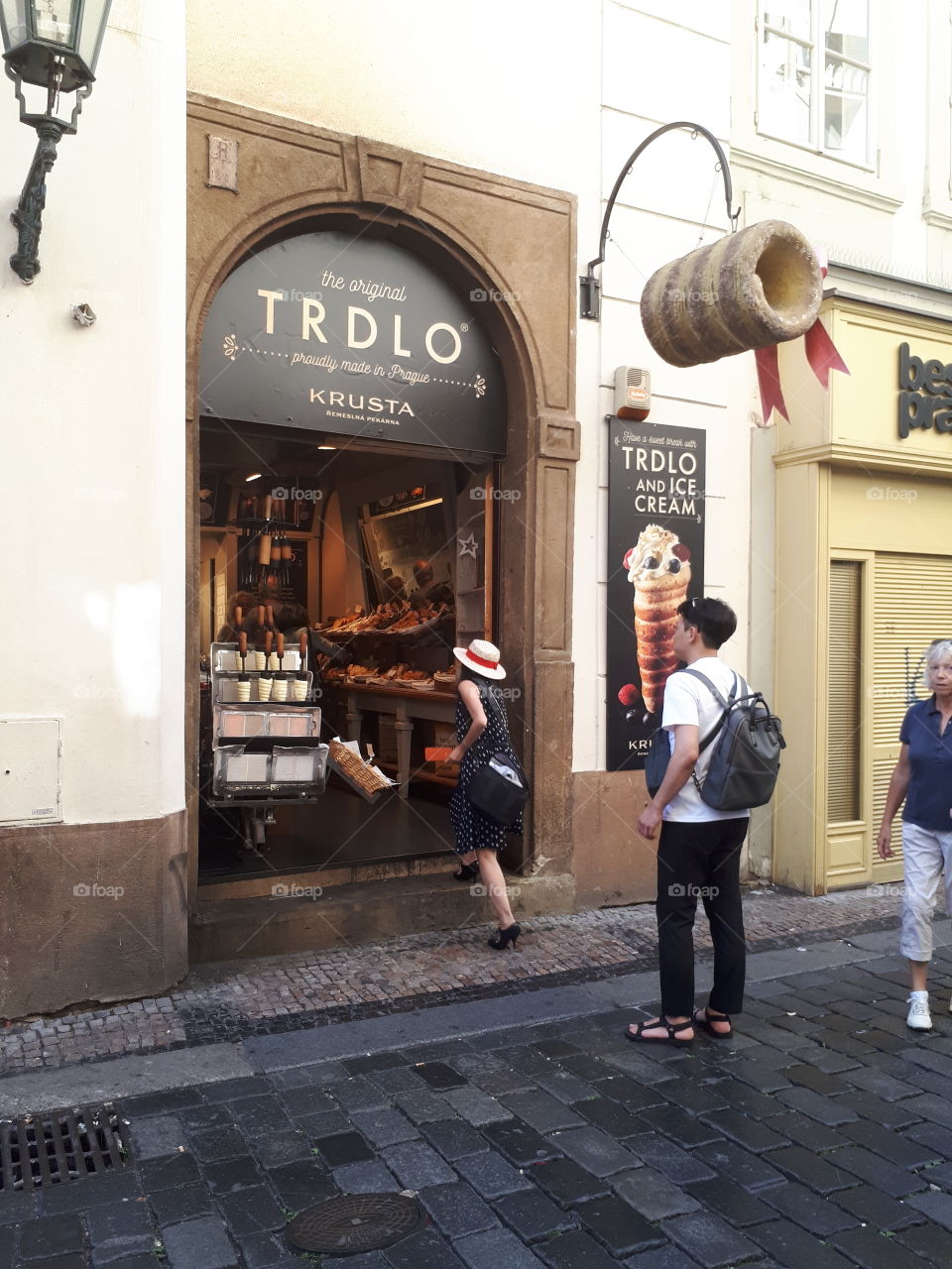 Tourists entering a shop in Prague to buy Trdelnik's; a traditional treat of rolled pastry coated in cinnamon and sugar.