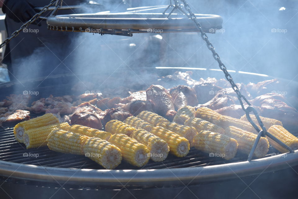 Turkey meat and corncobs being grilled during a street food festival