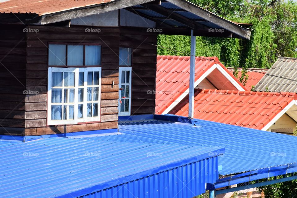 Old dark red wood wall with white windows typical residential house architecture details.  With bright tiled roof