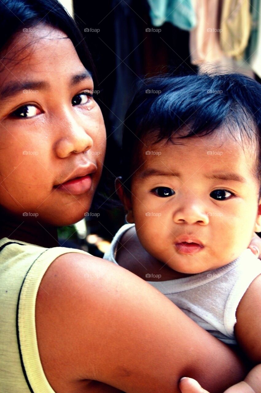 Asian siblings. Baby asian girl carried by her elder sister