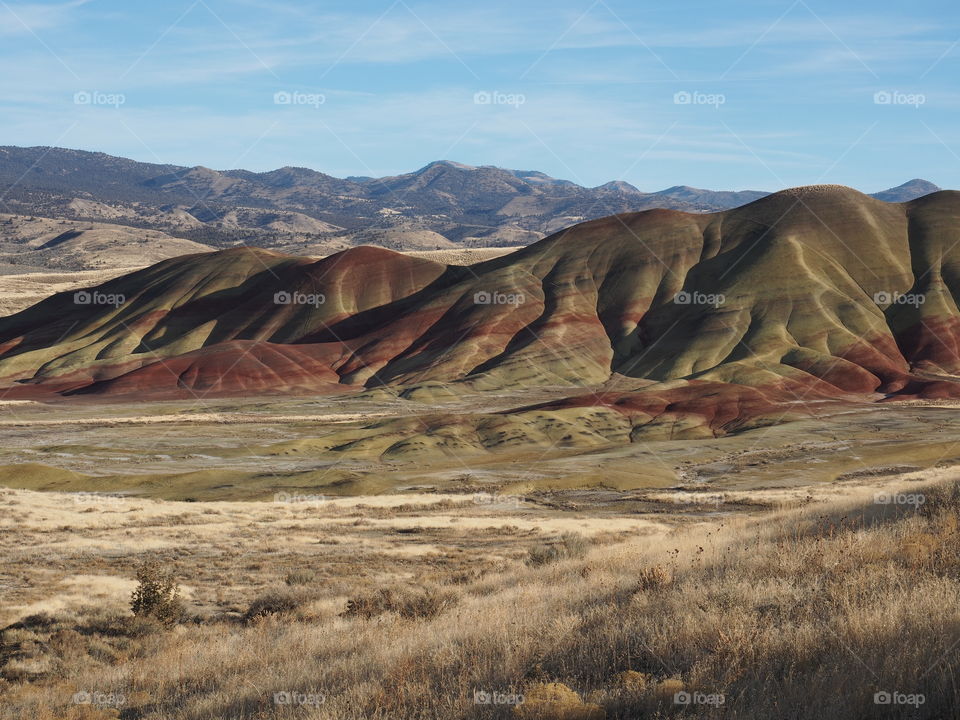 The textured Painted Hills in Eastern Oregon with layers of red, brown, green, and yellow on a sunny winter afternoon. 