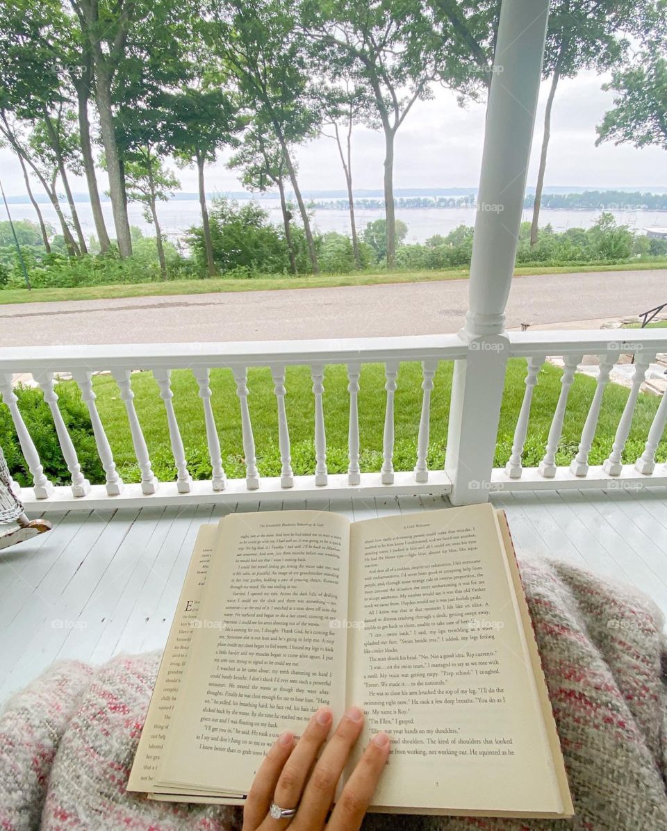 Someone sits and reads a book while overlooking a beautiful body of water.
