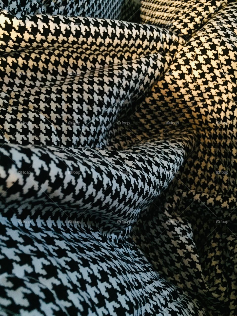The black and white houndstooth quilt. Grandmother made. Covering. Under the lamp light. 