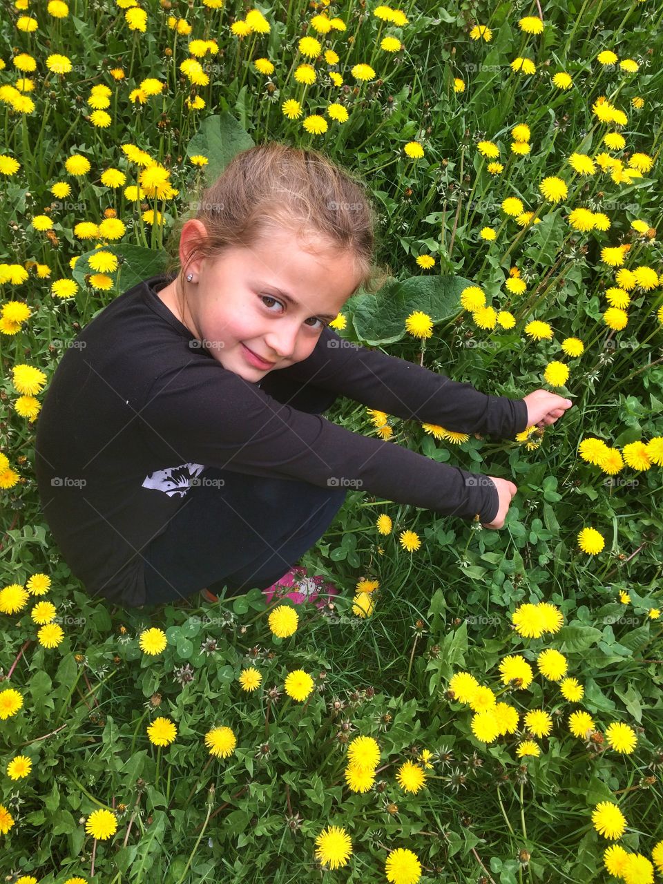 Smiling girl sitting on flower field
