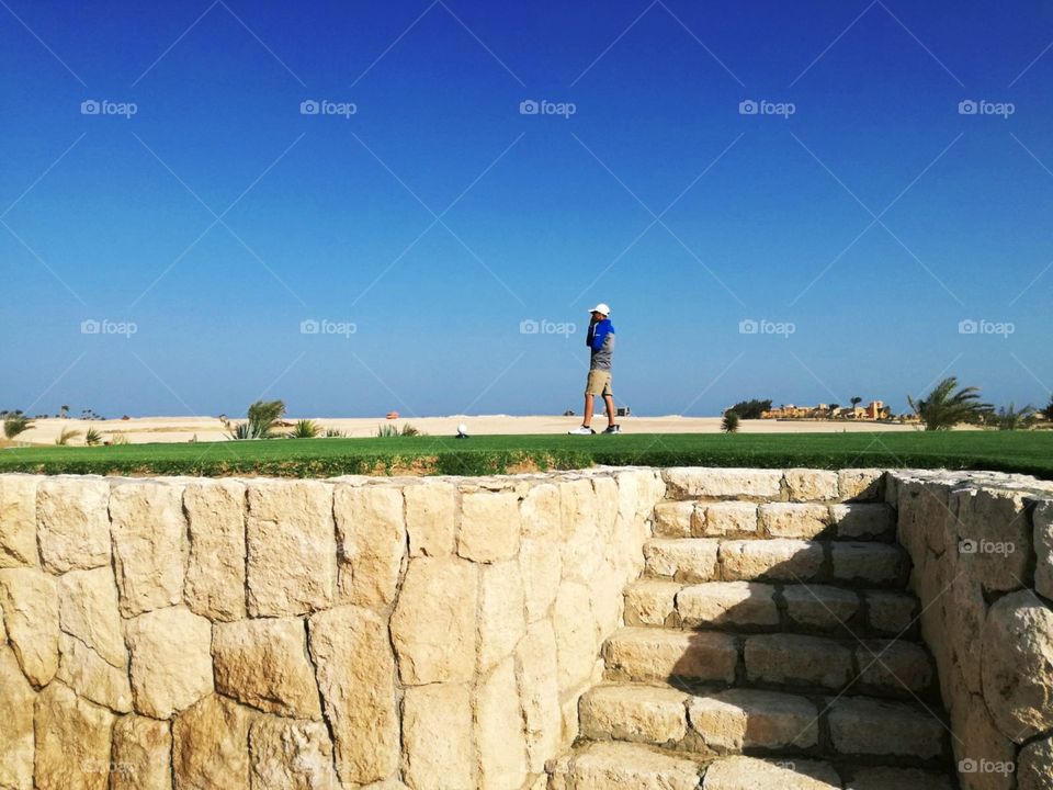 A beautiful view on golfer on the raised tee box. With beautiful desert and clean and blue sky background.