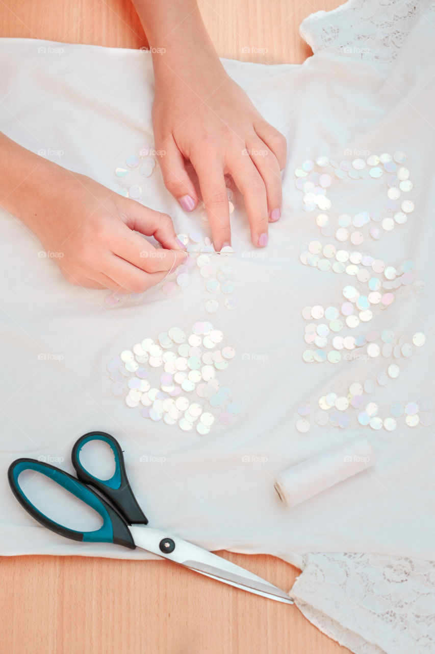 Girl decorating t-shirt with sequins following diy ideas