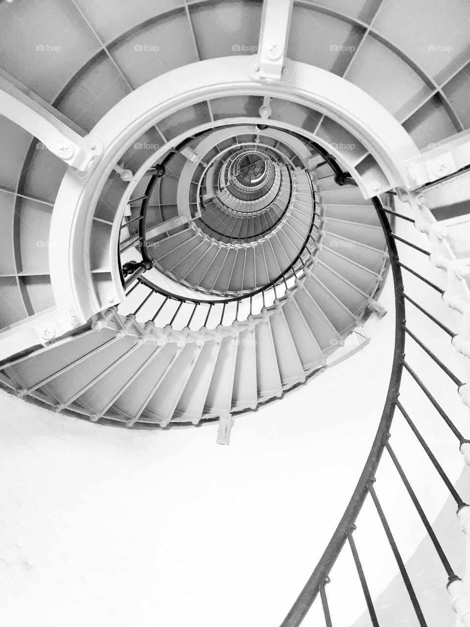 A black and white photo of the steep spiral staircase of the Ponce Inlet Lighthouse.