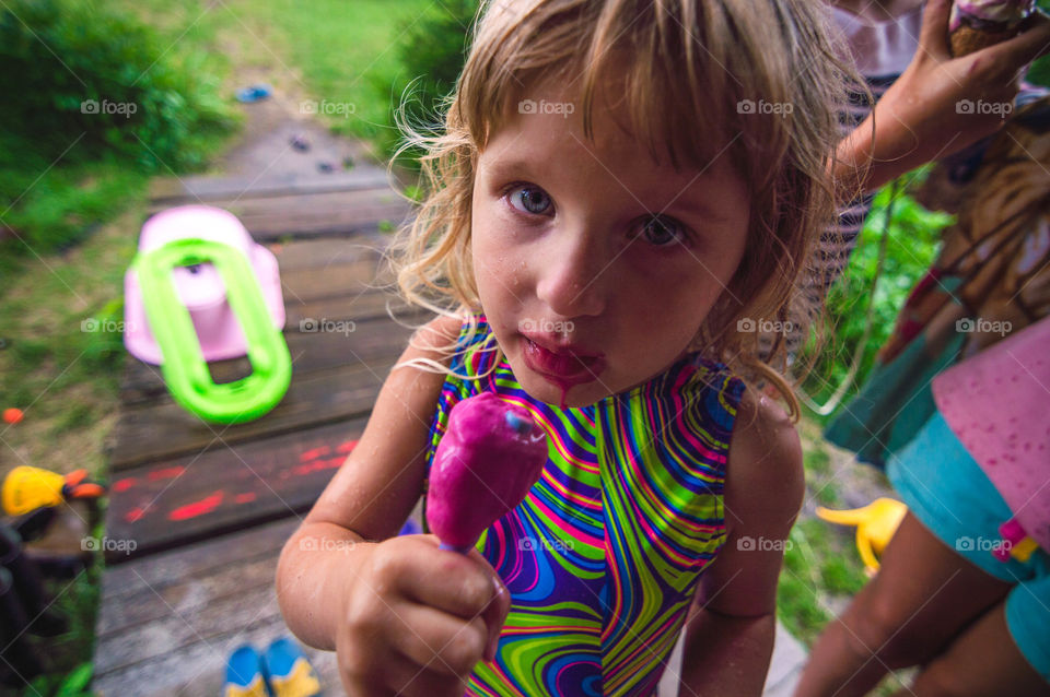 little girl is eating an ice cream messily