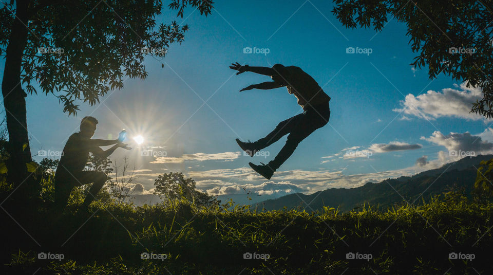 Composition of the silhouette of two guys imitating a kamehameha with the sunset