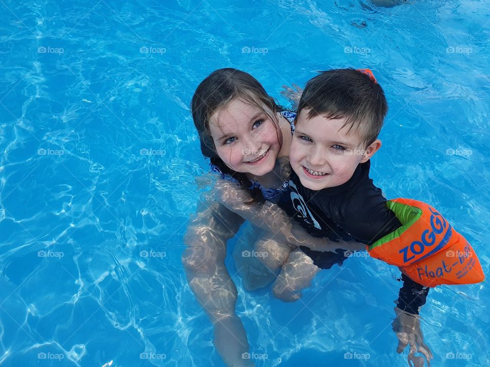 2 beautiful children having a fun day splashing around in the pool! 