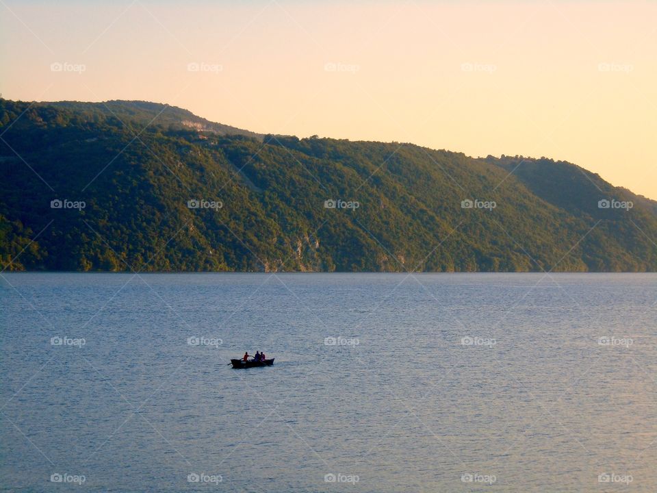 Boat sailing on lake at sunset