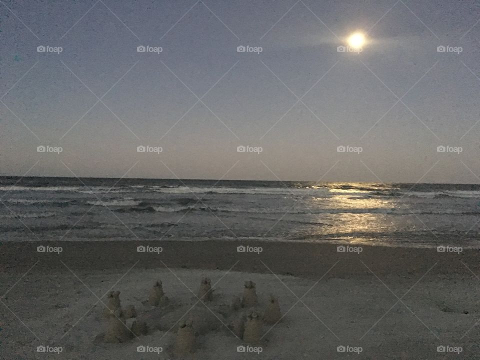 Moon reflecting on water with sandcastle 