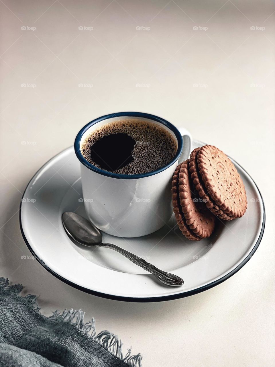 Hot black coffee in a white cup served with biscuits.