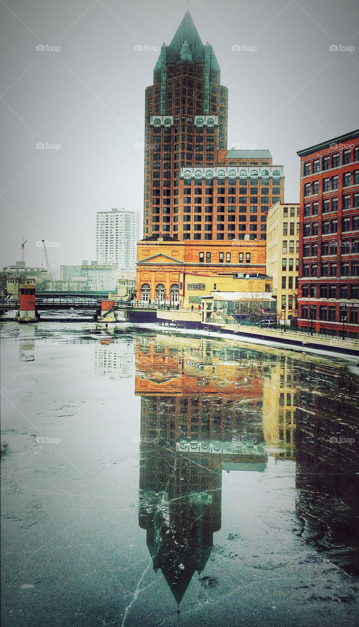 Reflections of office buildings on frozen river surface 