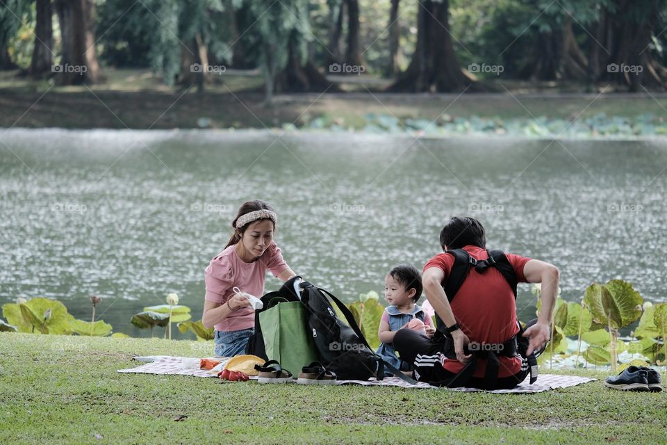 Portrait of happy Asian family, parents and daughter enjoying picnic meal in garden.Asian, Asian family, picnic, love, relationship, outdoors meal, park, family activities or happy garden concept