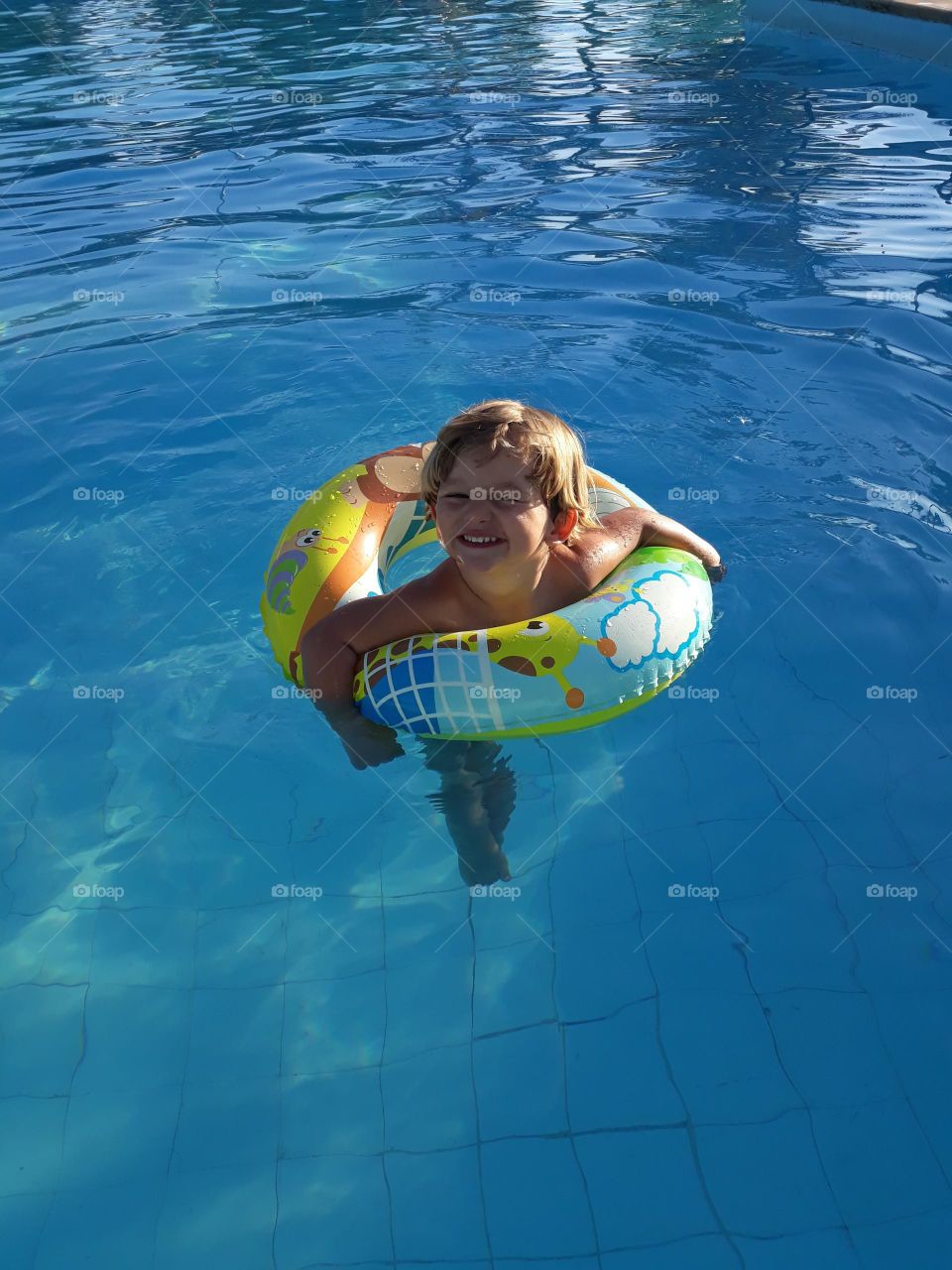 child playing with the float in the blue pool