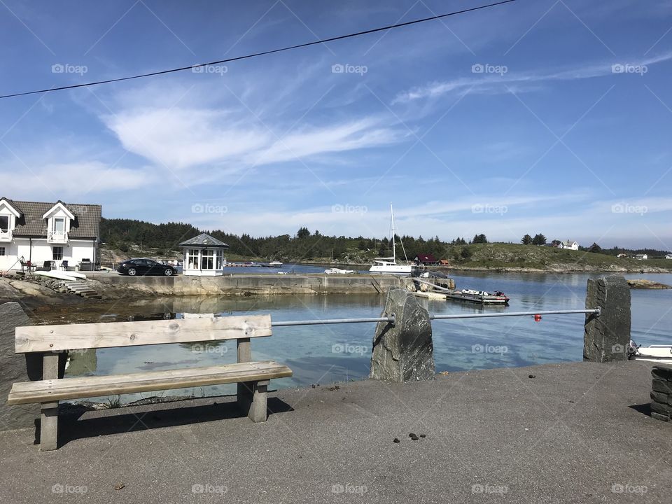 A bench in front of a beach. The beach is near “Skansen”. Skansen is a hiking spot in Austevoll in Norway.