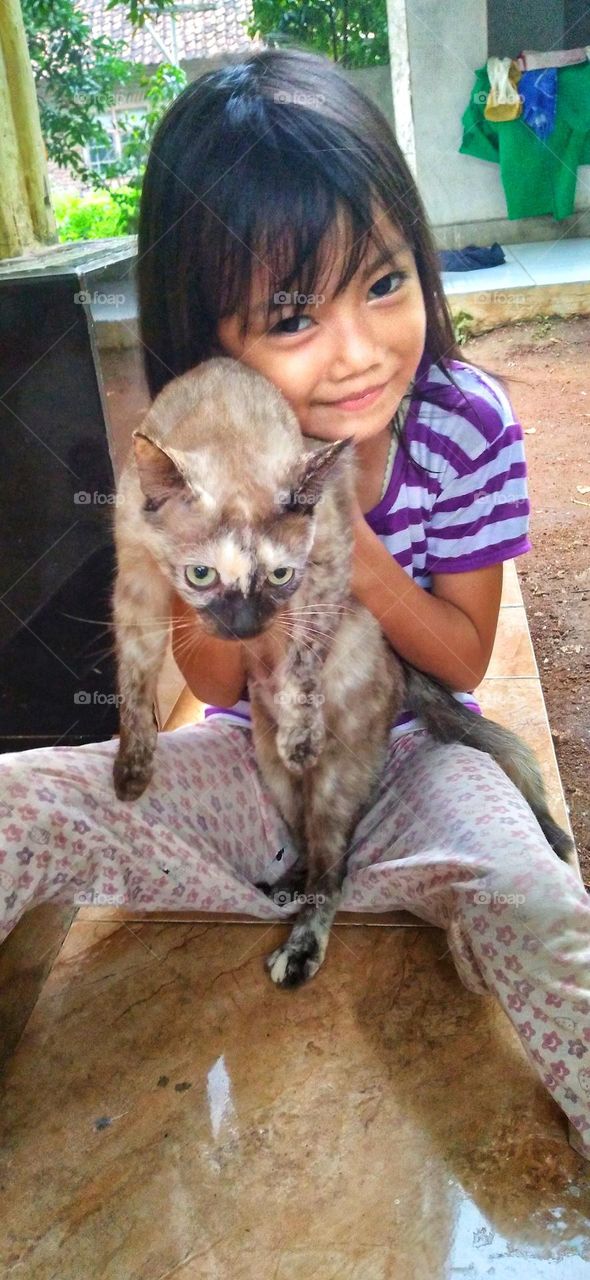 Cute little girl is carrying a cat