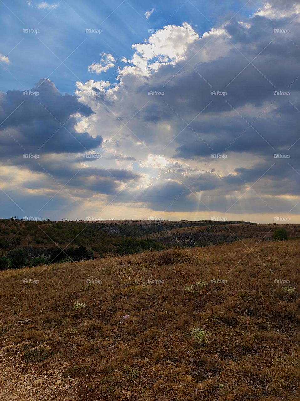 Beautiful clouds in nature / sun behind clouds / cloudy day on a field / sun rays made from clouds / blue sky