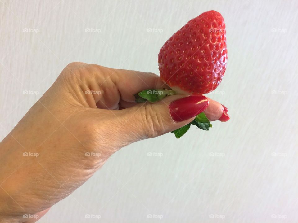 Woman's hand holding a strawberry