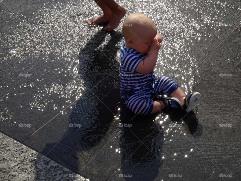 unhappy  sleepy young boy in water fountain square in centre of Nottingham, England