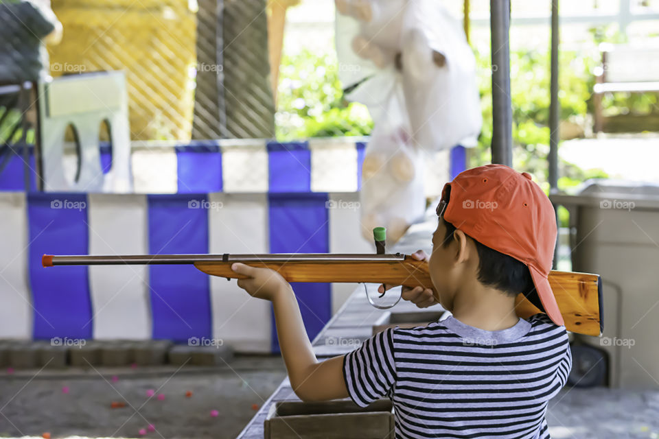 The boy holding a rifle toy made of wood.