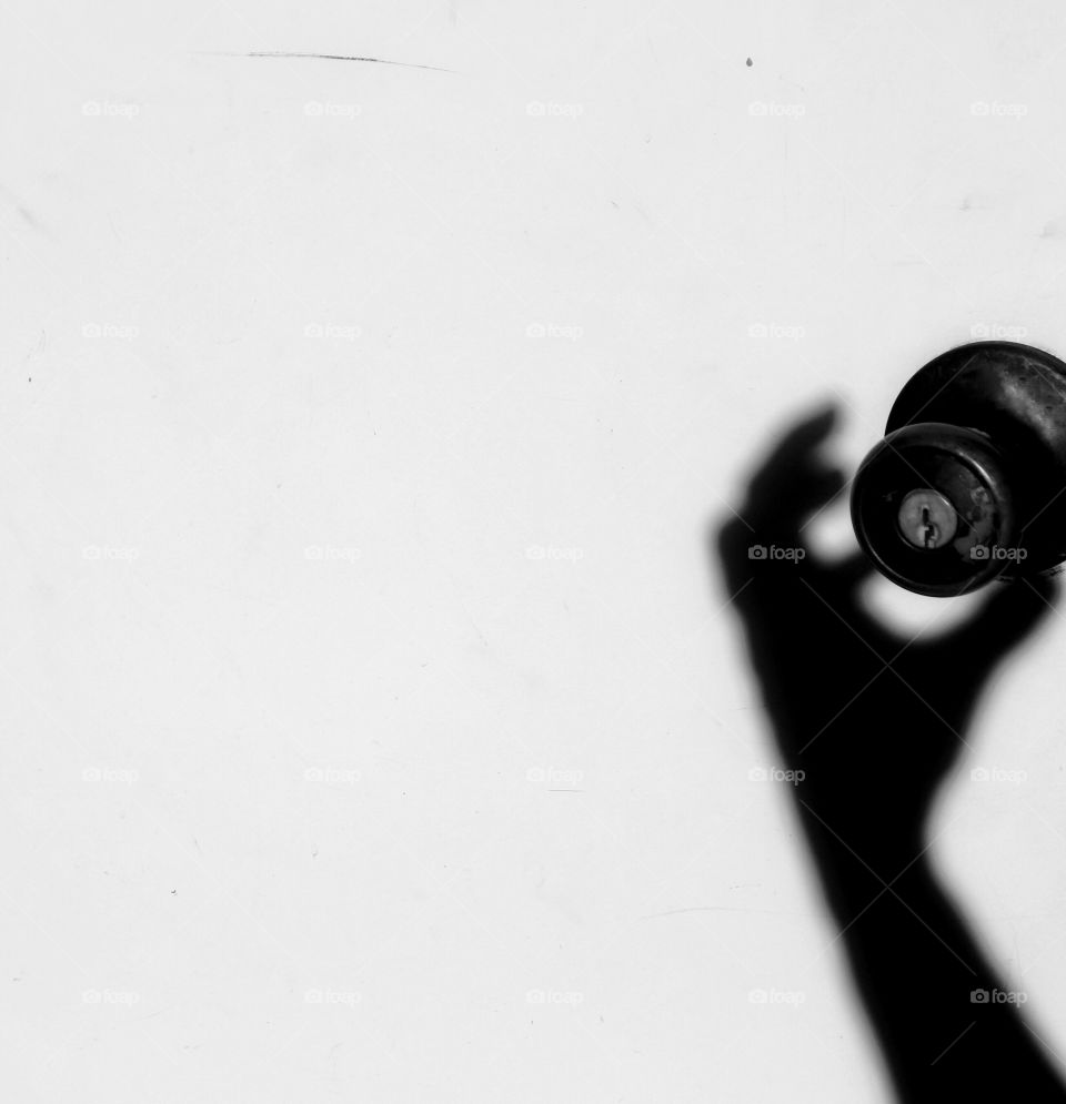 Silhouette of a hand trying to open a door with the doorknob!
