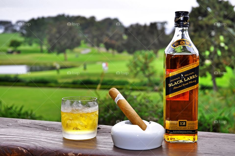 Relaxing after around of golf with a glass of whiskey and a nice cigar.