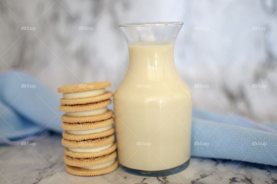 Oreo double stuff cookies stack next to a carafe of milk on a marble backdrop