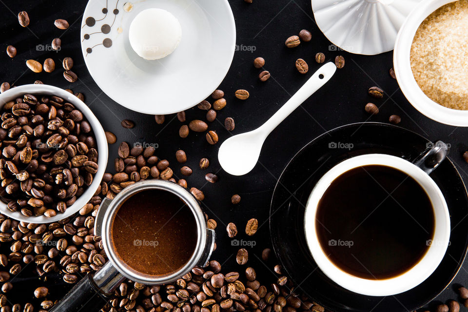 Beautiful close up of black and white coffee setting with beans filter cup spoon sugar and macaroon biscuit, in different circle and ellipse shapes.