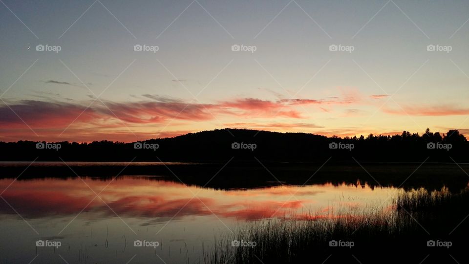 Mountains and clouds reflected on a lake at sundown with a pink sky