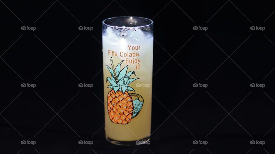 Inviting Icy cold fruity drink Piña Colada cup against velvet black background