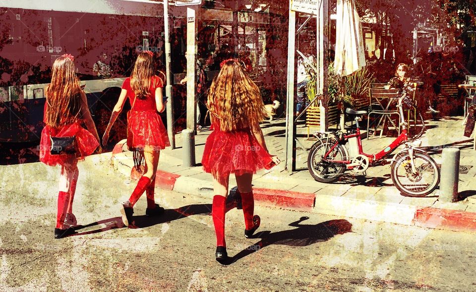 Girls with red dresses crossing the street  