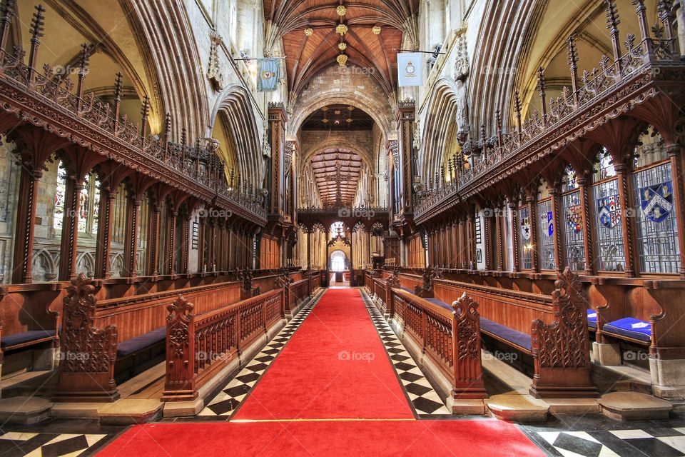 The interior of a large church with red carpets and ornate wooden pews.