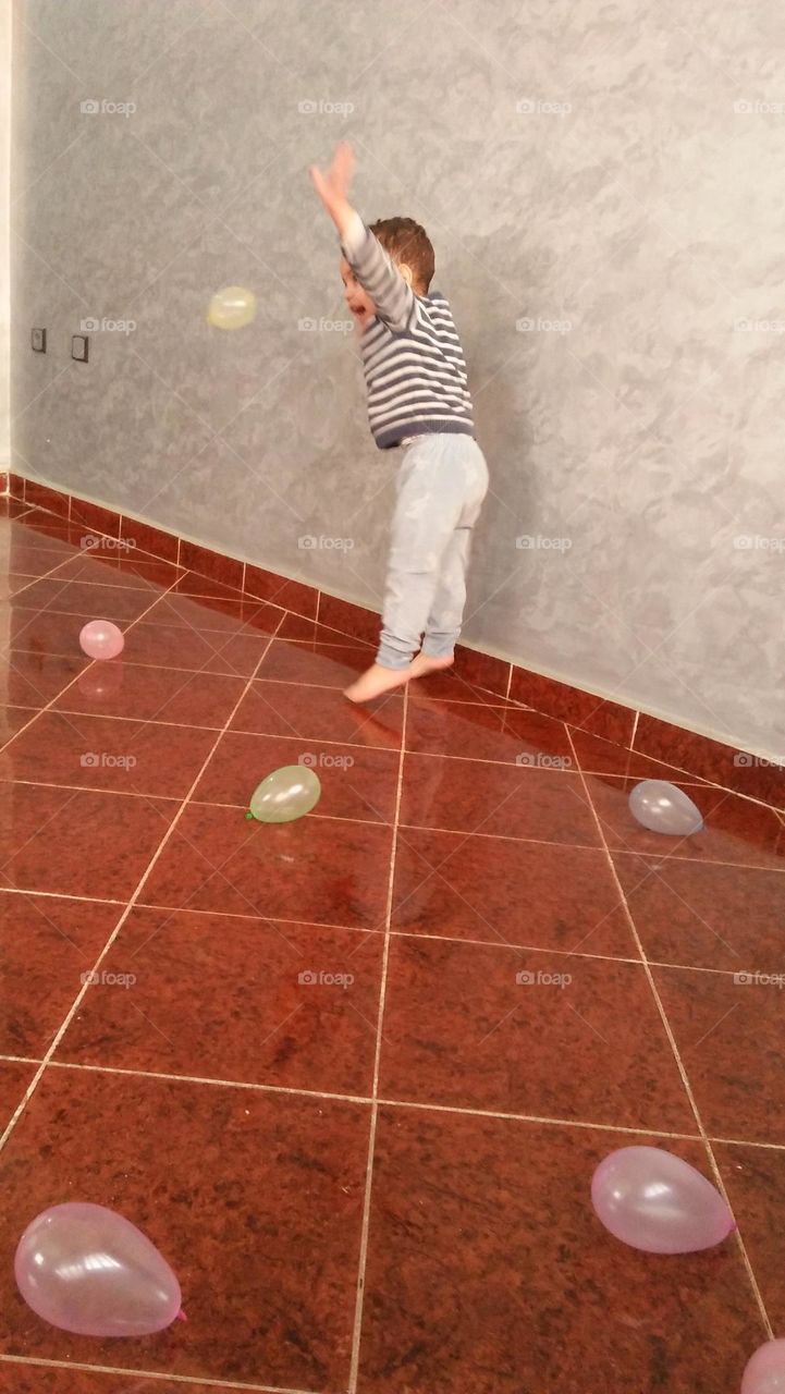 A little boy joyfully playing with balloons.