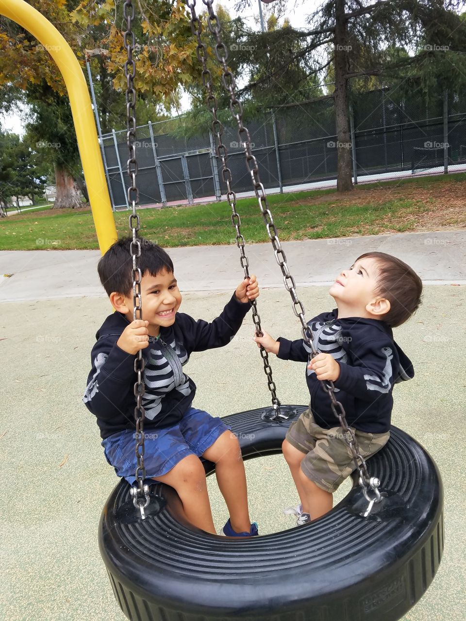 Brothers playing on tire swing