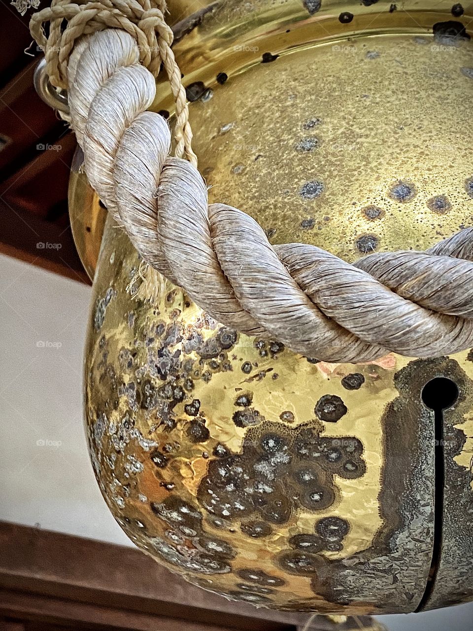Old traditional metal gold-colored bell with twisted rope at a shrine in Tokyo, Japan.