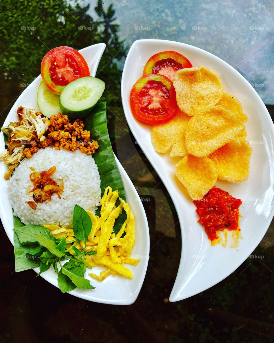 Traditional coconut rice with eggs, chicken and crackers in yin and yang plates.