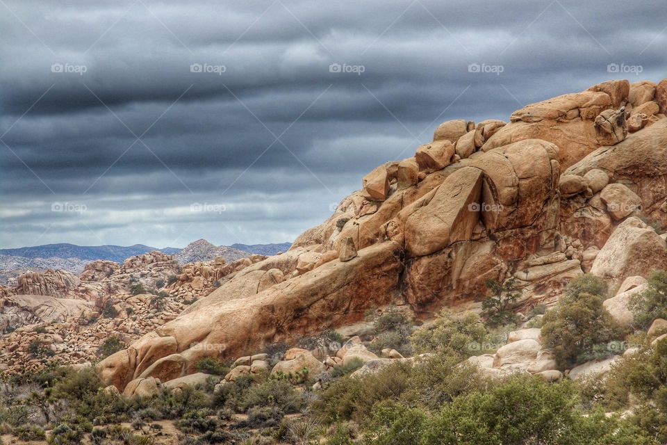 Stunningly beautiful rock formations at Joshua Tree National Park in California, with a cloud cover in the sky , moody feeling as if a storm is coming