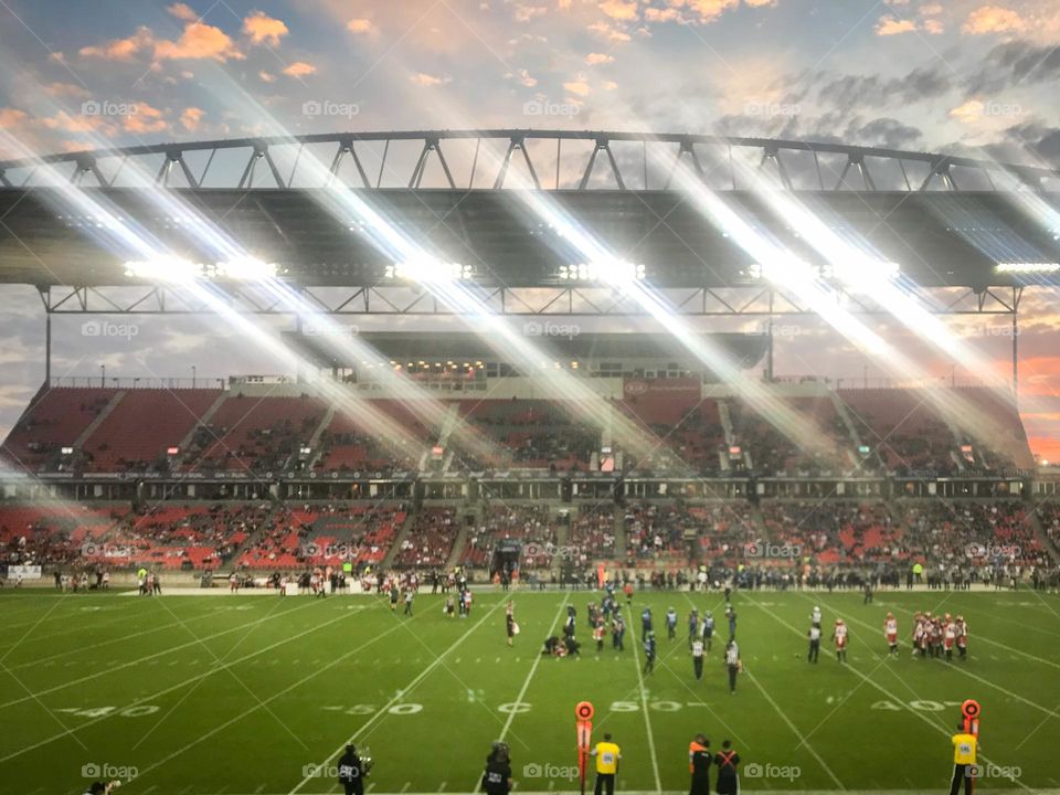 A glimmer of happiness in the evening at a football game just before the sun sets.
