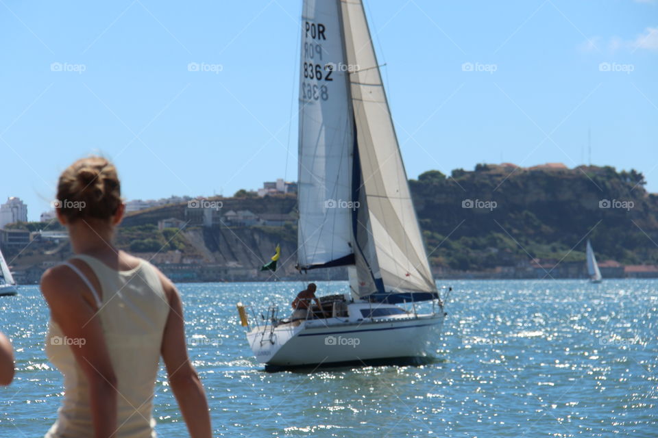 girl contemplating sail boat. walk along Lisbon riverside